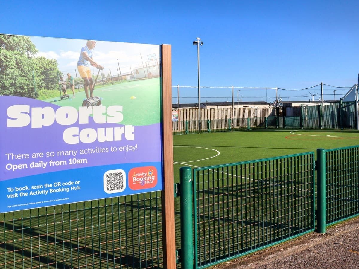 A sports court with a fence and a sign advertising the court's availability.