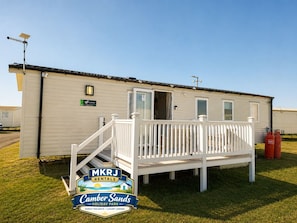 Une maison mobile dotée d’un porche blanc et d’une rampe d’accès, portant les inscriptions « MKRJ Rentals » et « Camber Sands Holiday Park ».