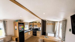 Una cocina moderna con armarios de madera, horno integrado y un comedor con mesa y banco de madera.