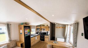 Une cuisine moderne avec des meubles en bois, une cuisinière intégrée et un coin repas comprenant une table et un banc en bois.