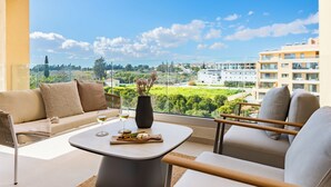 Un balcon moderne agrémenté d’un canapé, de chaises et d’une table où sont disposés des verres et un vase.