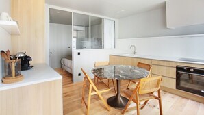 A modern kitchen with a marble table, wooden chairs, and a built-in oven.