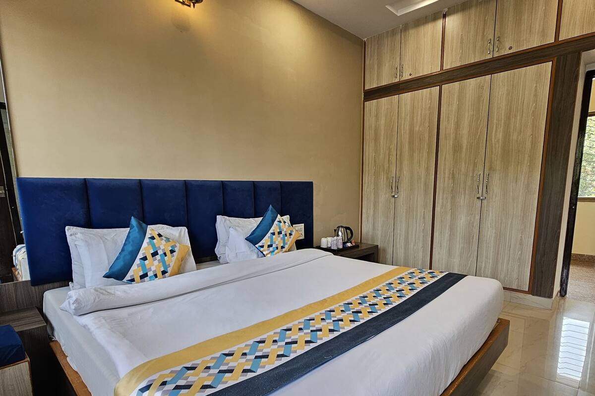Una cama grande con cabecera azul, un armario de madera y un ventilador de techo.