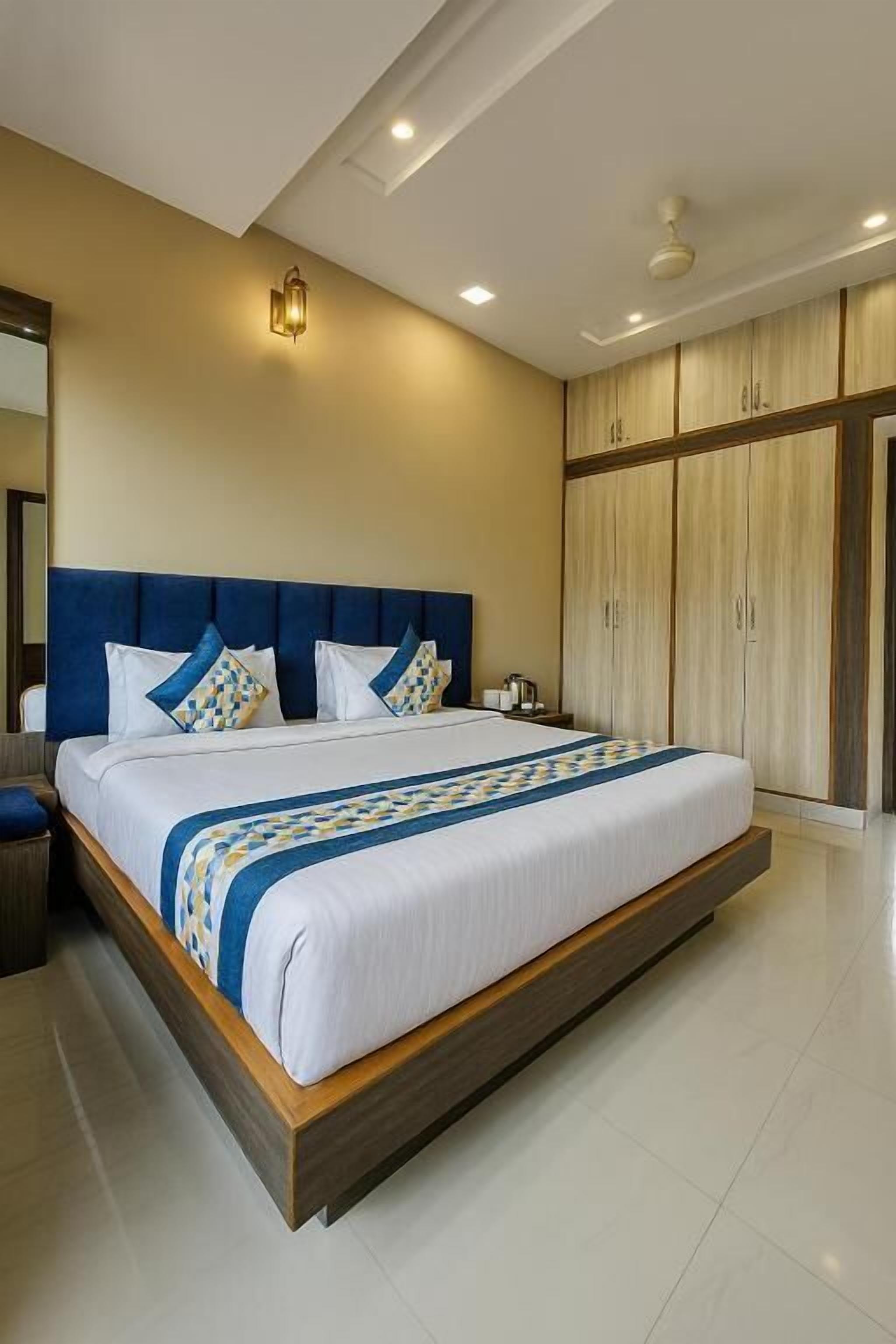 Une chambre d’hôtel moderne avec un grand lit, une tête de lit en bois et une armoire aux portes coulissantes.