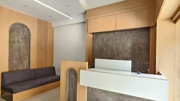Una habitación moderna y minimalista con escritorio empotrado, sofá oscuro y ventilador de techo.