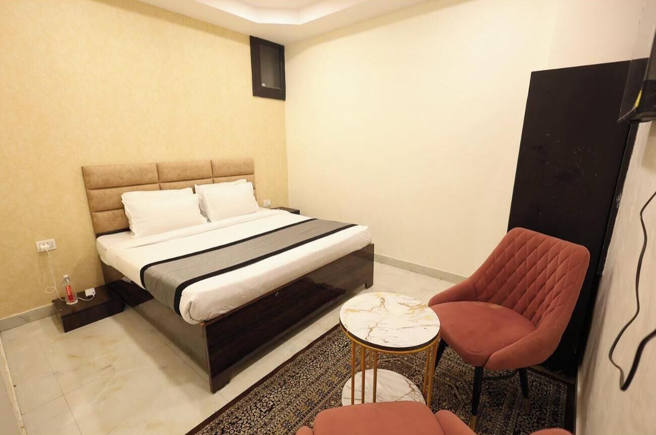 Une chambre d’hôtel avec un lit, une petite table ronde, une chaise rouge et une armoire.