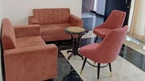 Et moderne loungeområde med sofasæt, et rundt bord og en enkelt lænestol.