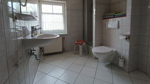A modern bathroom with a large sink, toilet, and shower area. - Rohrdachhus- vacation apartment 2 (Mönchgut)