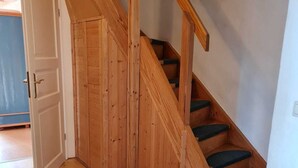 A wooden staircase with green carpeted steps, a white door, and a wooden floor. - Rohrdachhus- vacation apartment 2 (Mönchgut)