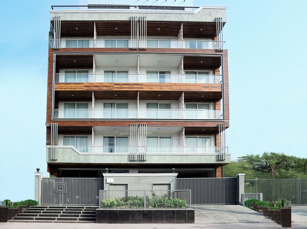 A multi-story building with balconies, a gated entrance, and a staircase leading to the entrance. - Suisen Hospitality Pvt Ltd (Gurugram)