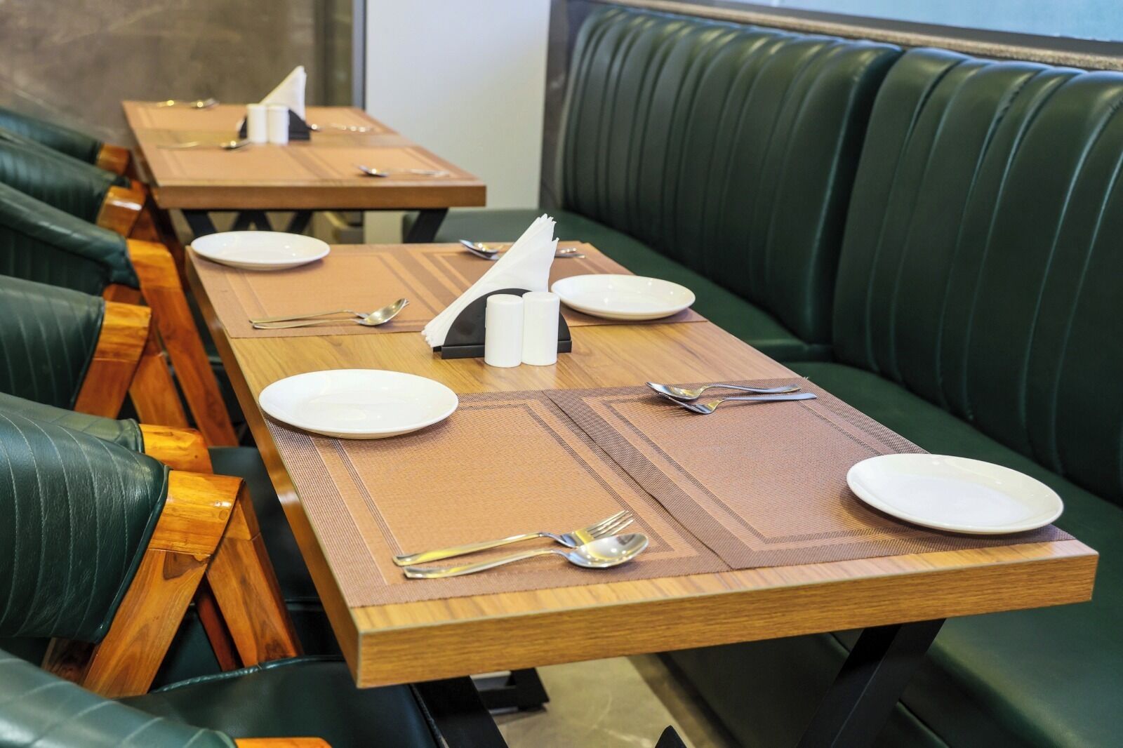 A restaurant with wooden tables and green upholstered booths.