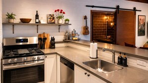 A modern kitchen with stainless steel appliances, a wooden countertop, and a brick wall backsplash. - Ocean View Balcony | 4 Min Walk to Beach | Romantic Theme (Manhattan Beach)