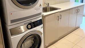 Eine übereinander angeordnete Waschmaschine und ein Trockner in einer Küche mit Spüle und Schränken.