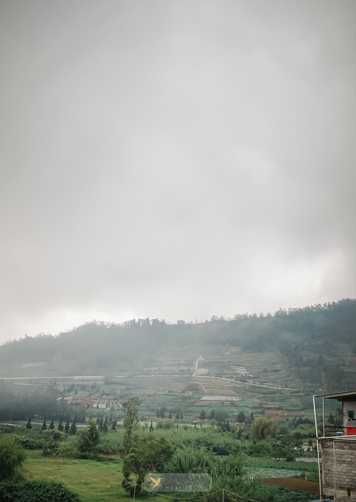 A rural landscape with terraced fields, a road, and a building with a red roof.