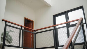 Un interior moderno con una escalera, una puerta de madera y un ventanal grande.