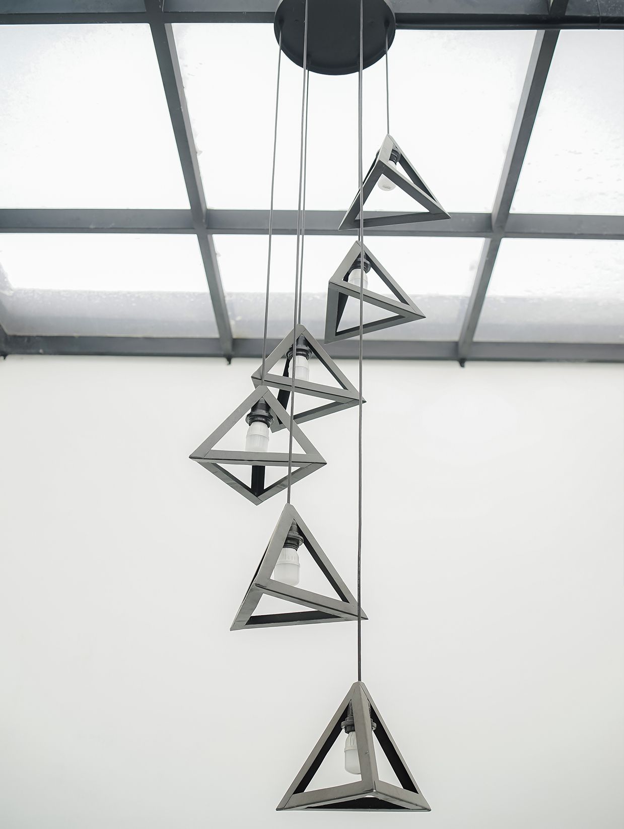 A modern chandelier with geometric shapes and a visible brand name 'NEXURA HOSPITALITY'.