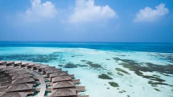 A resort with overwater bungalows, clear turquoise water, and a clear sky.