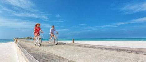 Une promenade en bois menant à une plage, avec un ciel dégagé.