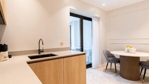 Een moderne keuken met een spoelbak, houten kastjes en een eethoek met een ronde tafel en stoelen.