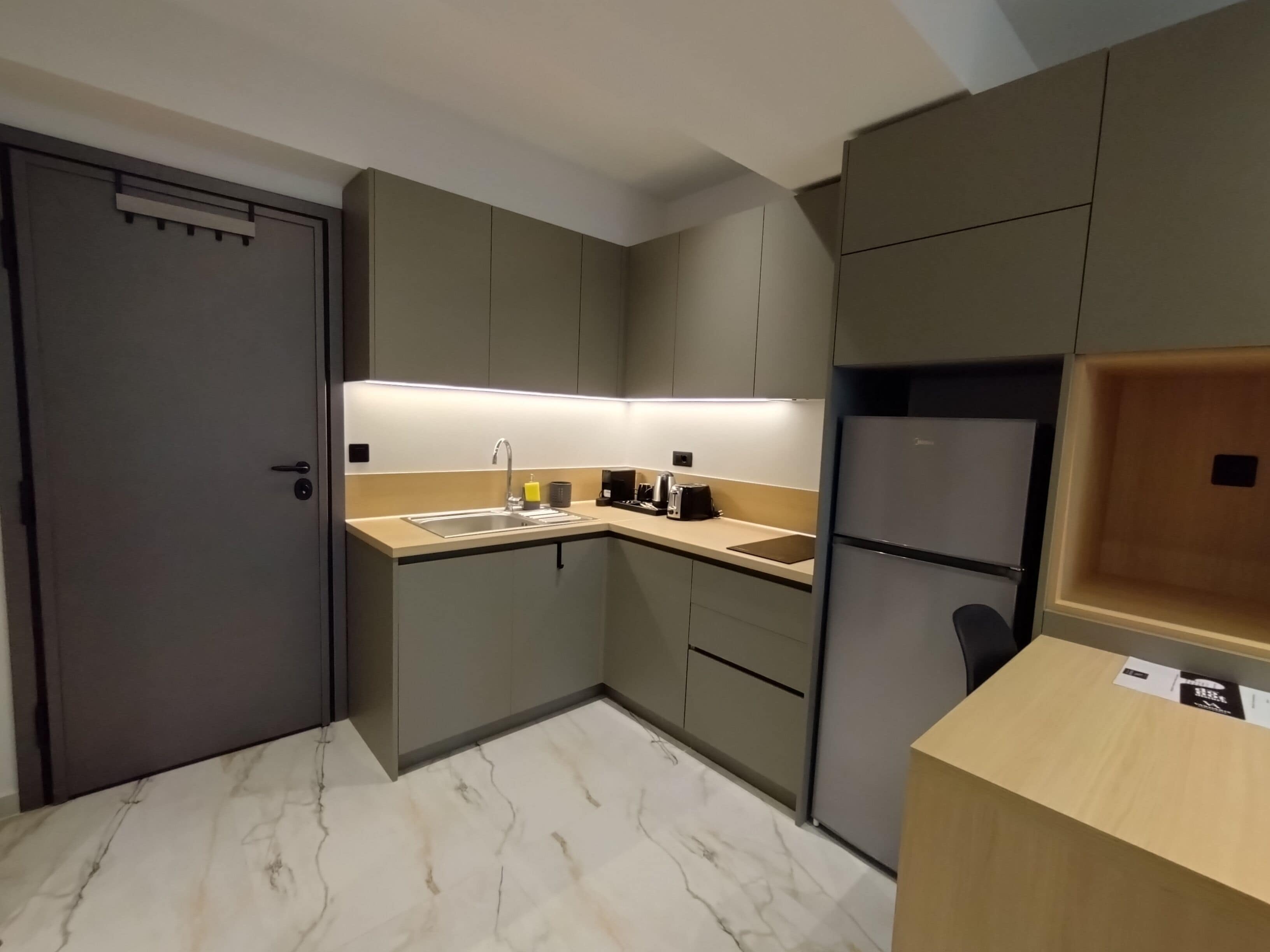 A compact kitchen with a sink, countertop, and a refrigerator.