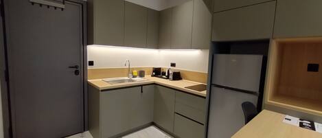 A compact kitchen with a sink, countertop, and a refrigerator.