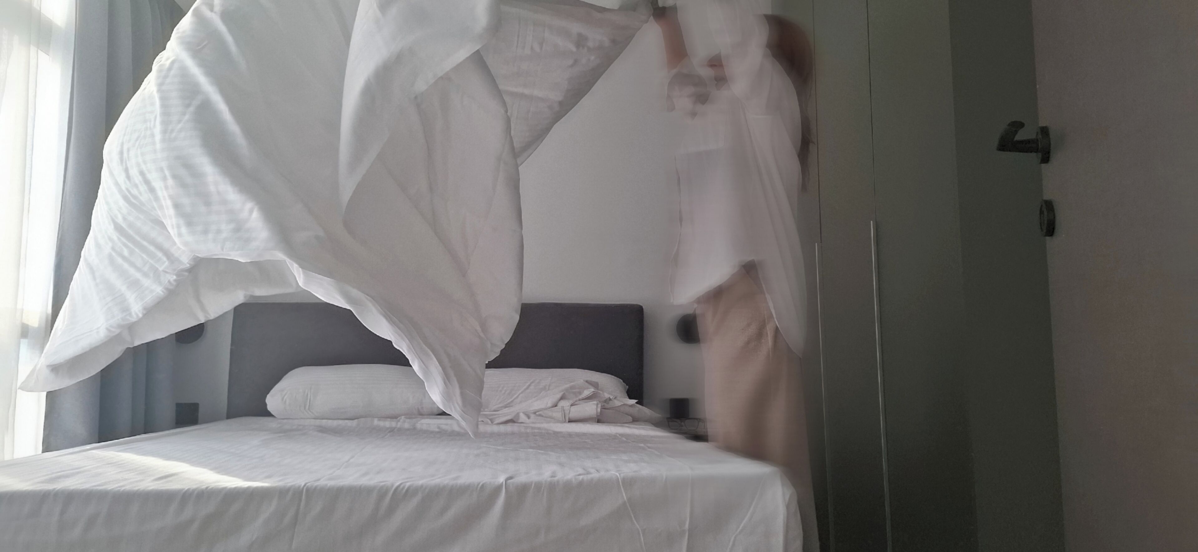 A bed with white bedding and a white canopy.
