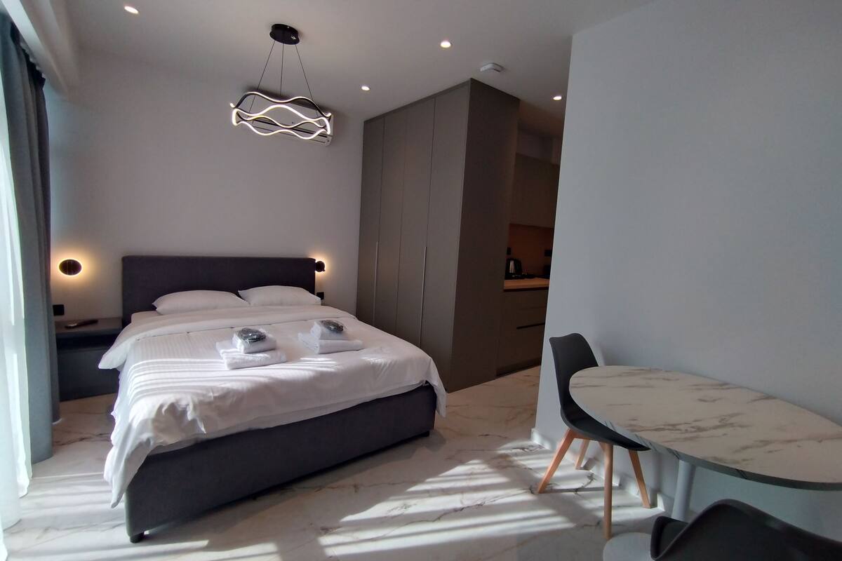 Ein modernes Hotelzimmer mit einem ordentlich bezogenen Bett, einem kleinen runden Tisch und einem Stuhl.