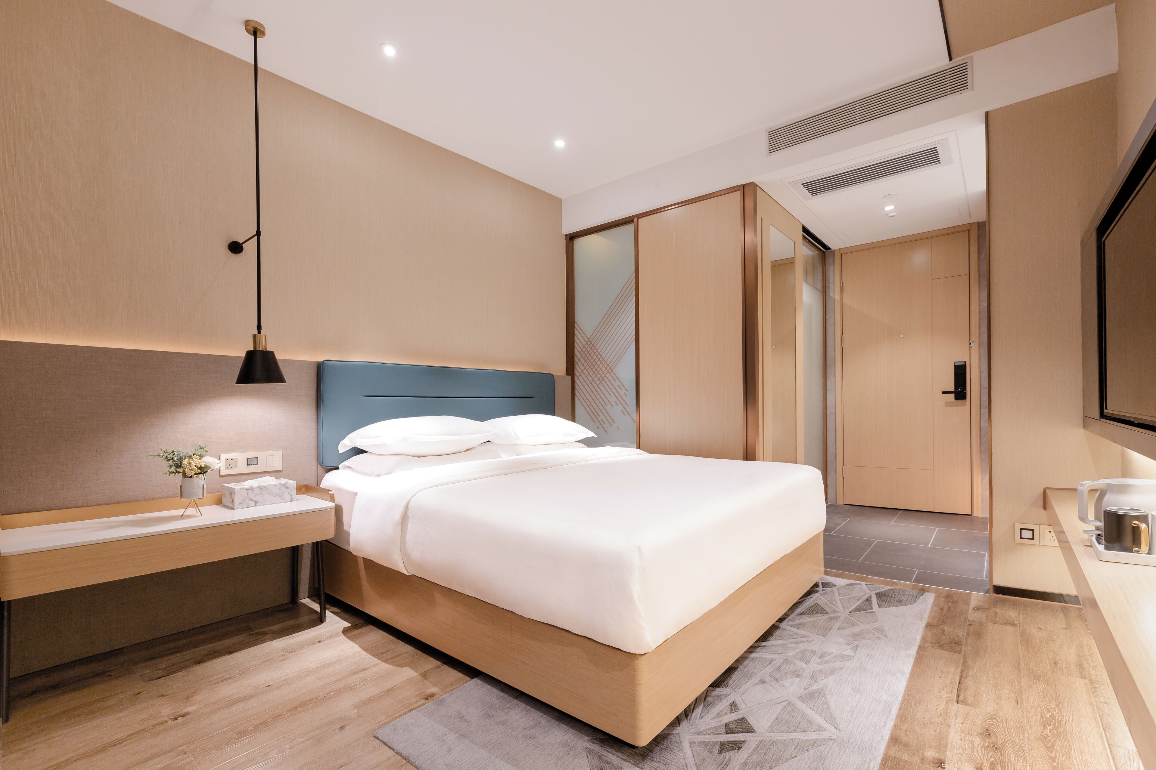 A modern bedroom with a bed, bedside table, and a built-in wardrobe.