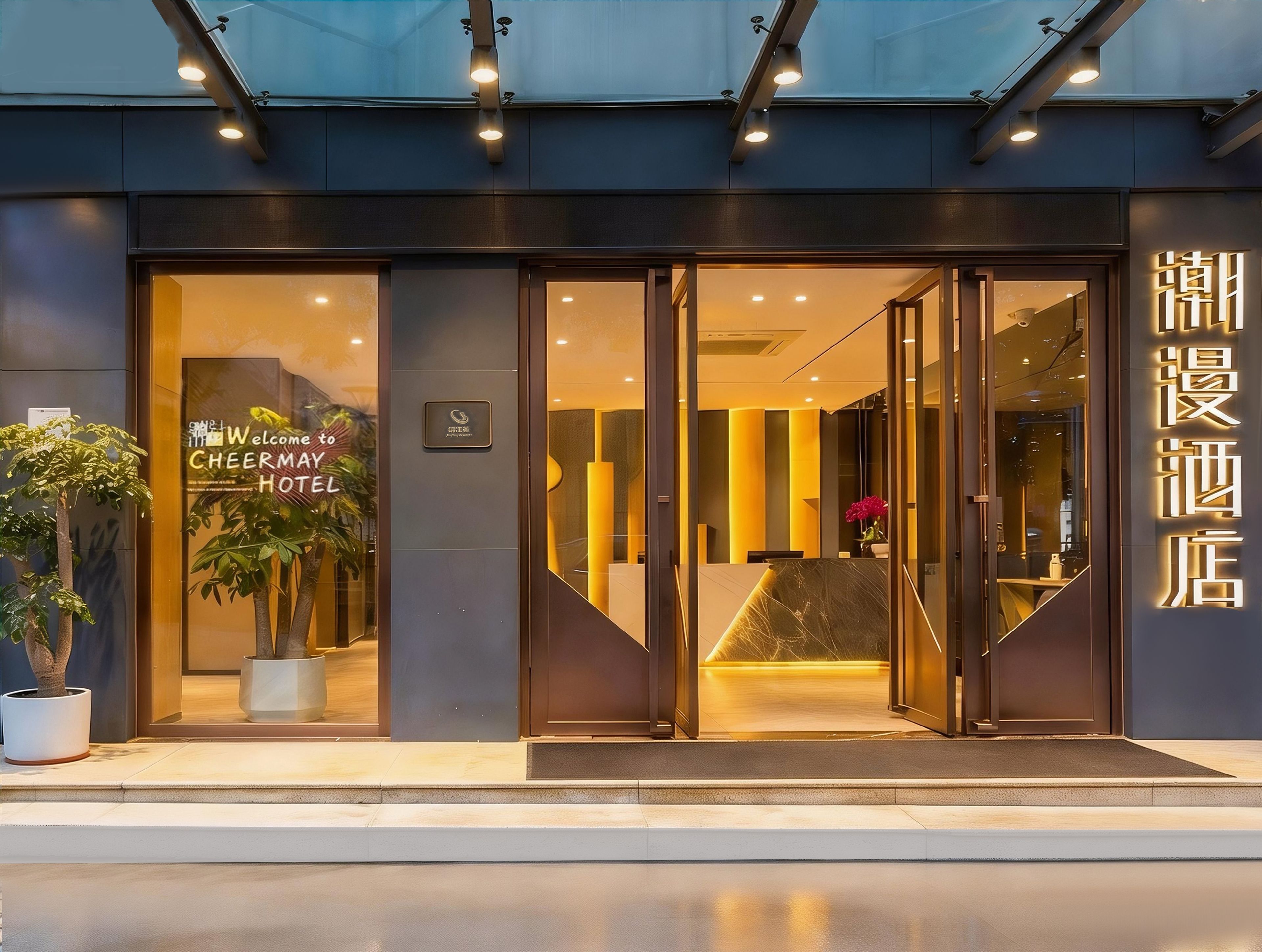 A hotel entrance with a reception desk, glass doors, and a sign indicating the hotel name.