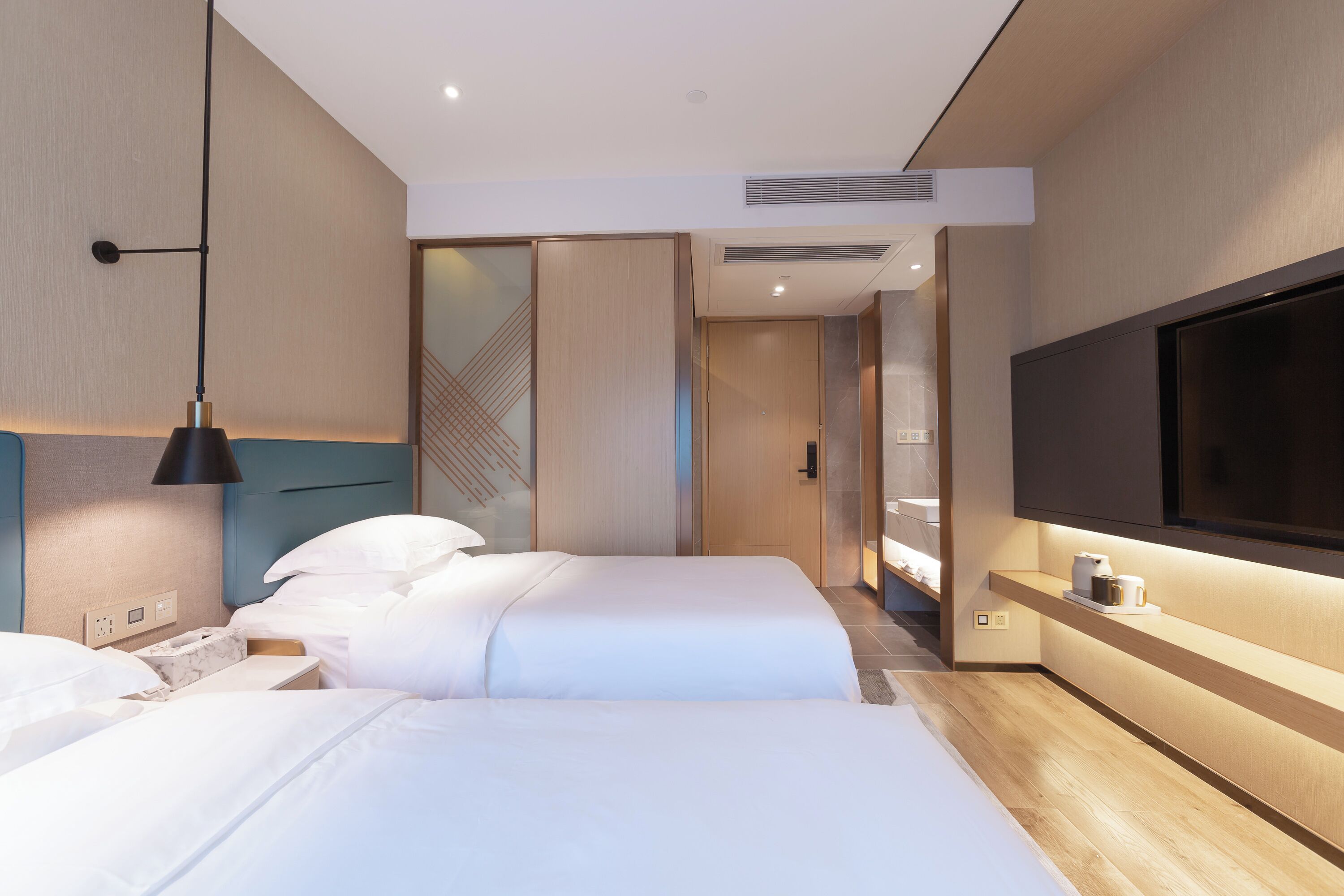 Een moderne hotelkamer met een groot bed, nachtkastjes, een televisie en een trap naar een andere kamer.