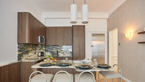 A modern kitchen with a marble countertop, wooden cabinets, and a bar area with stools. - Superb Apartment on the Champs Elysees (Paris)