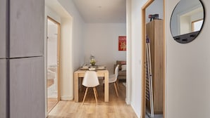 Een kleine leefruimte met een eethoek, een spiegel en een zichtbare badkamer.