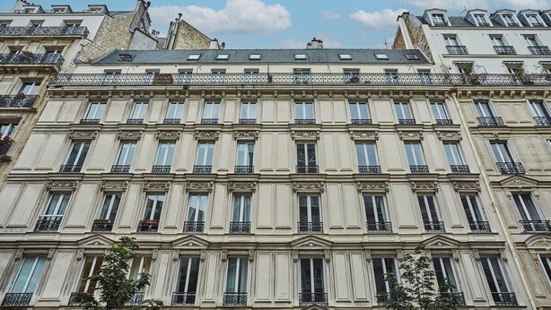 A multi-story building with a classical architectural style, featuring symmetrical windows and ornate balconies. - Charming Apartment - Eiffel Tower/Trocadero (Paris)