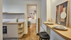 A modern kitchen with a wooden countertop, built-in shelves, and a dining area with a table set for two. - Charming Apartment - Eiffel Tower/Trocadero (Paris)