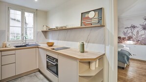 A modern kitchen with a wooden countertop, built-in oven, and a window. - Charming Apartment - Eiffel Tower/Trocadero (Paris)