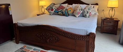 A neatly made bed with floral pillows, a wooden headboard, and two bedside lamps.