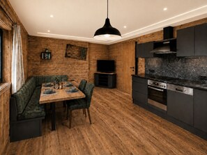 A modern kitchen with wooden flooring, a dining area with a bench, and built-in appliances.