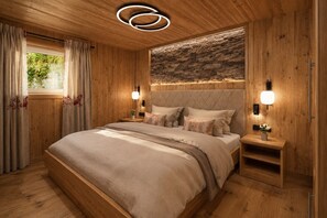 A wooden bedroom with a large bed, bedside tables, and a stone accent wall.