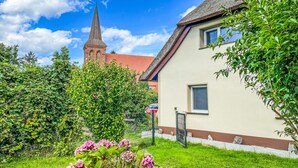 A building with a red roof and a church steeple in the background.