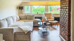 A modern living room with a sectional sofa, a round coffee table, and a brick accent wall.