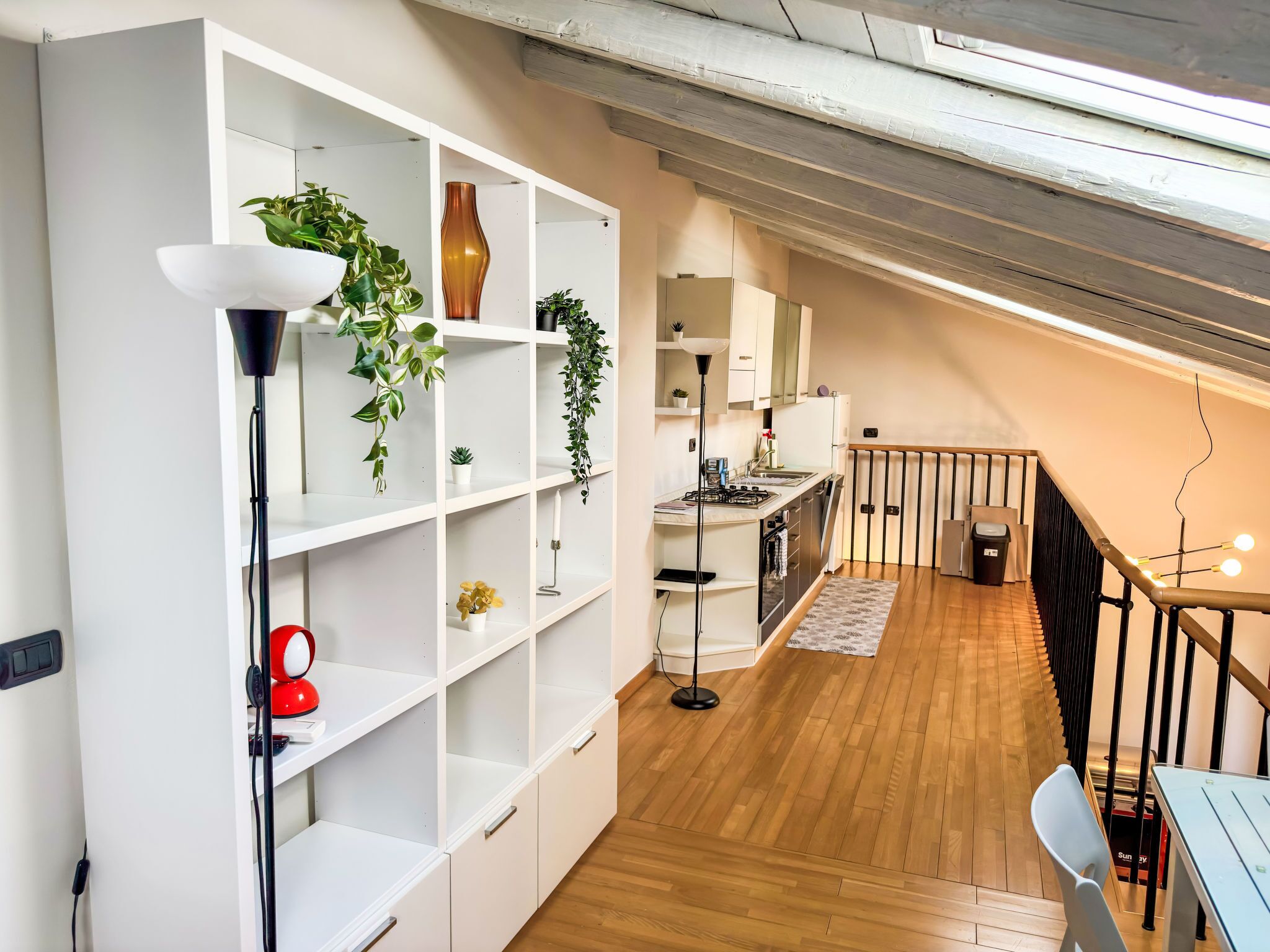 A modern kitchen with white cabinetry, a wooden floor, and a dining area with a table and chairs.
