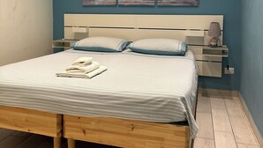 A bedroom with a bed, bedside tables, and artwork on the wall. - BlueBay Holiday Home (Torre del Greco)