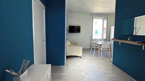 A modern interior with a hallway leading to a dining area, a TV mounted on the wall, and a white cabinet with pens. - BlueBay Holiday Home (Torre del Greco)
