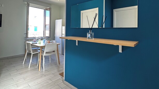 A modern kitchen with a blue accent wall, wooden countertop, and a white door. - BlueBay Holiday Home (Torre del Greco)