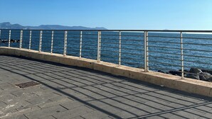 A paved walkway with a metal railing overlooking a body of water. - BlueBay Holiday Home (Torre del Greco)