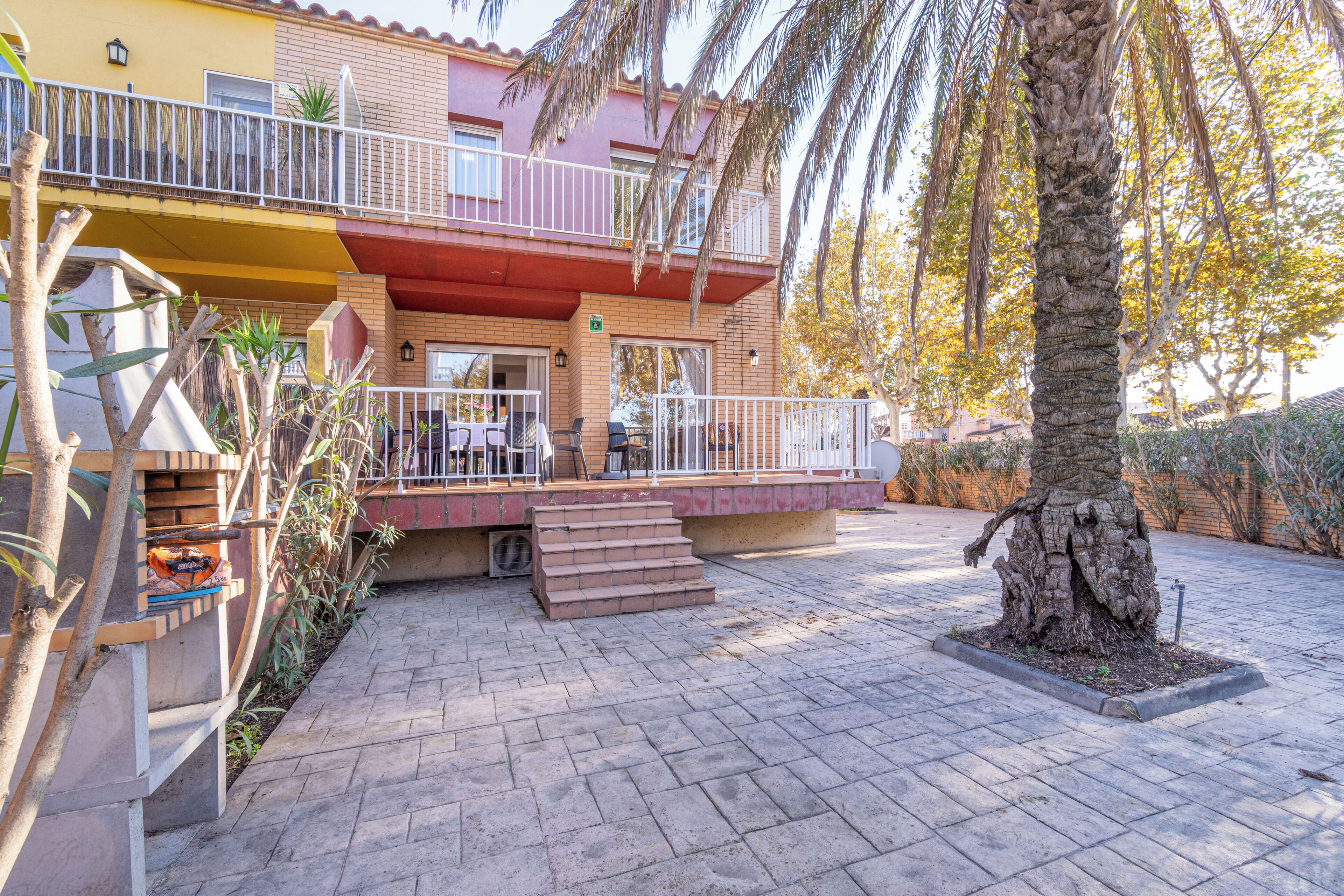 A two-story building with a balcony, outdoor seating, and a palm tree.