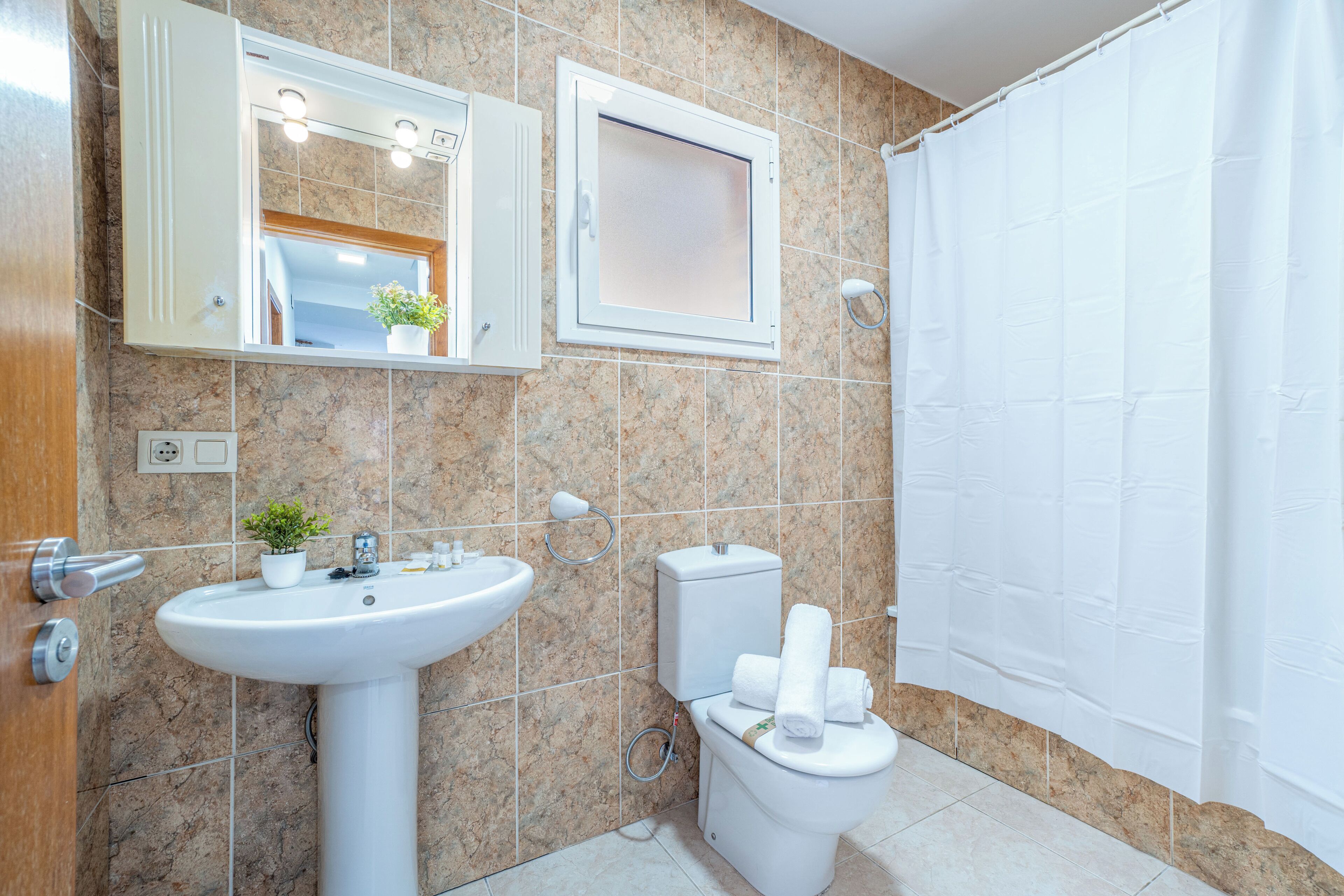 A bathroom with a sink, toilet, and shower curtain.