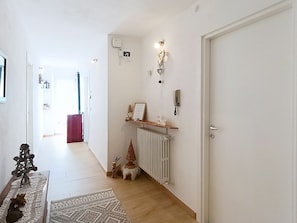 A hallway with a radiator, a door, and a shelf with a 'Home' sign.