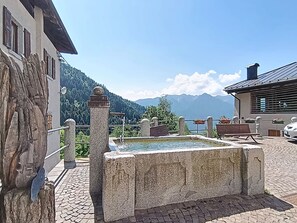 A stone fountain, a bench, and a view of a lake with mountains in the background. - Apartment Festér by Interhome (Ragoli)