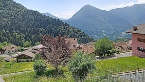 Un paysage montagneux avec des maisons et un arbre au premier plan.